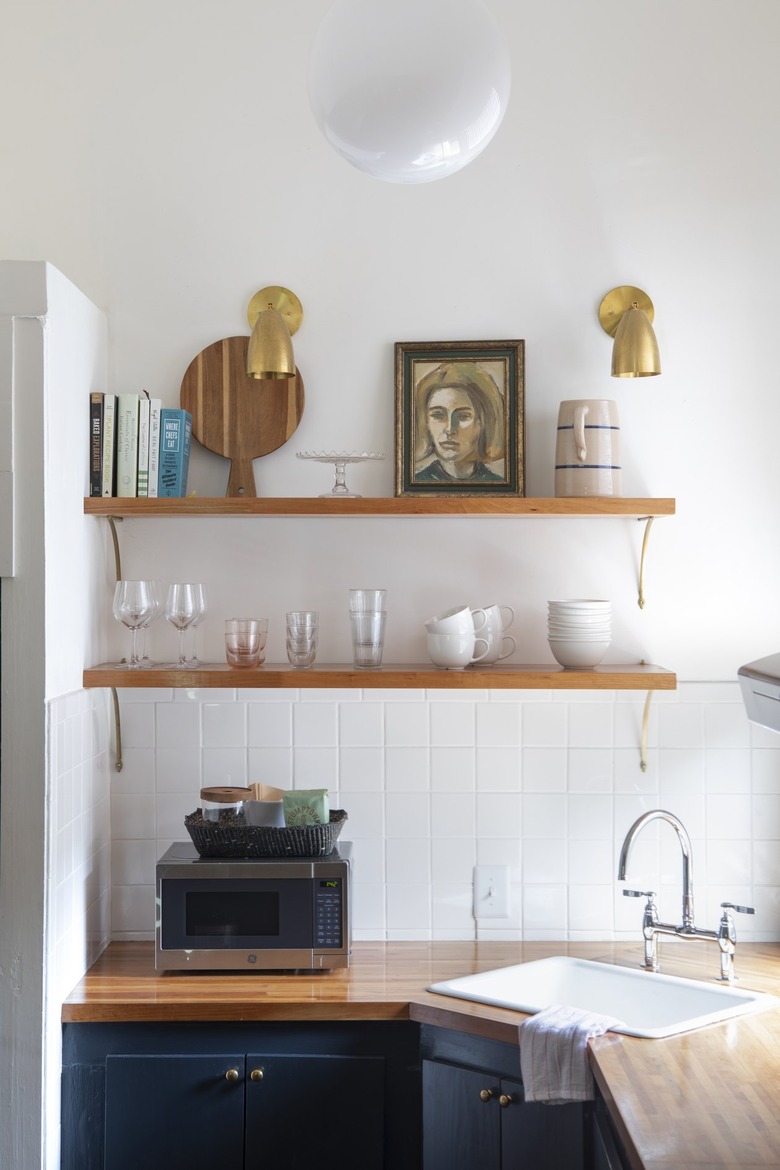 honey-colored wood shelves hold glasss, cups, and artwork