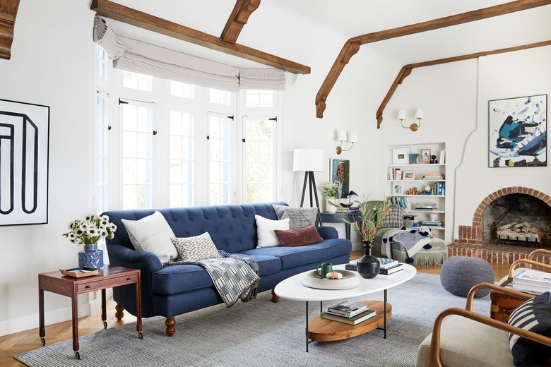 navy blue living room idea by Emily Henderson with tufted blue sofa and brick fireplace