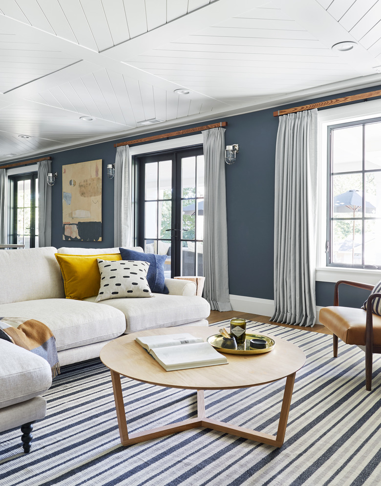 navy blue living room idea designed by Emily Henderson with striped area rug and floor-to-ceiling drapery