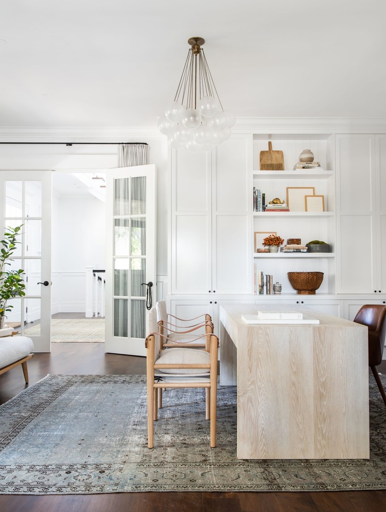 neutral home office with modern chandelier and white built-in shelves