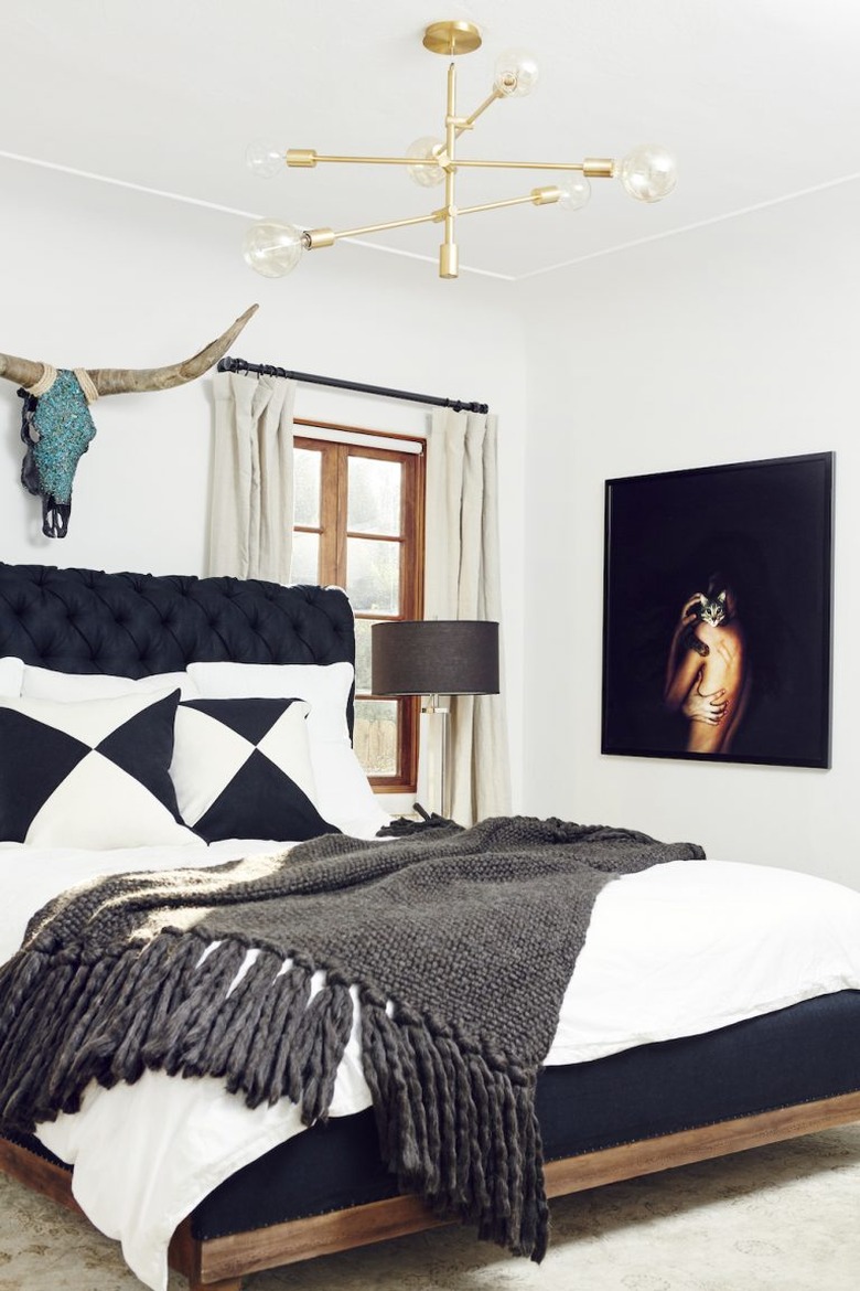 black and white bedroom idea with upholstered headboard and brass chandelier