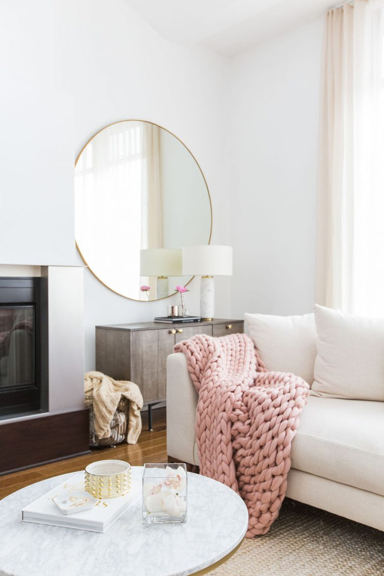 living room mirror idea with chunky knit blanket and large round mirror