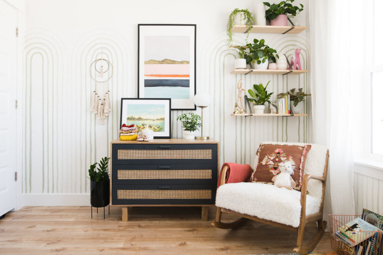 Vintage baby nursery idea with patterned wall paper and wall shelving with chest of drawers and rocker