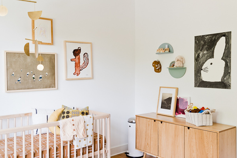 Artistic baby nursery idea with mobile hanging above crib and art on walls