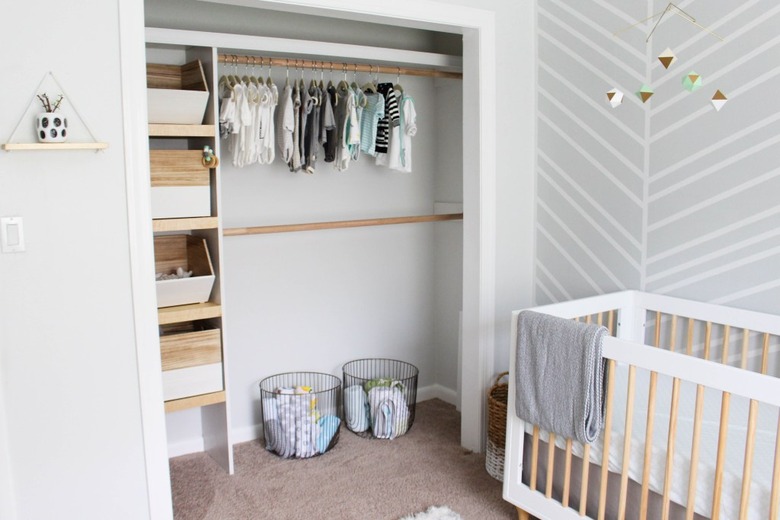 minimalist nursery organization in closet with storage bins baskets and clothing rods