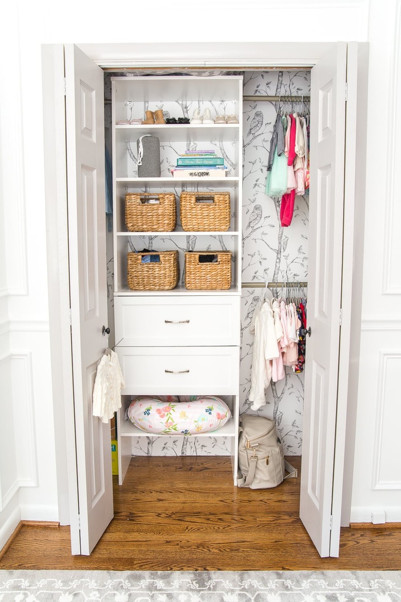 nursery organization with drawers and shelving and wallpaper on the wall