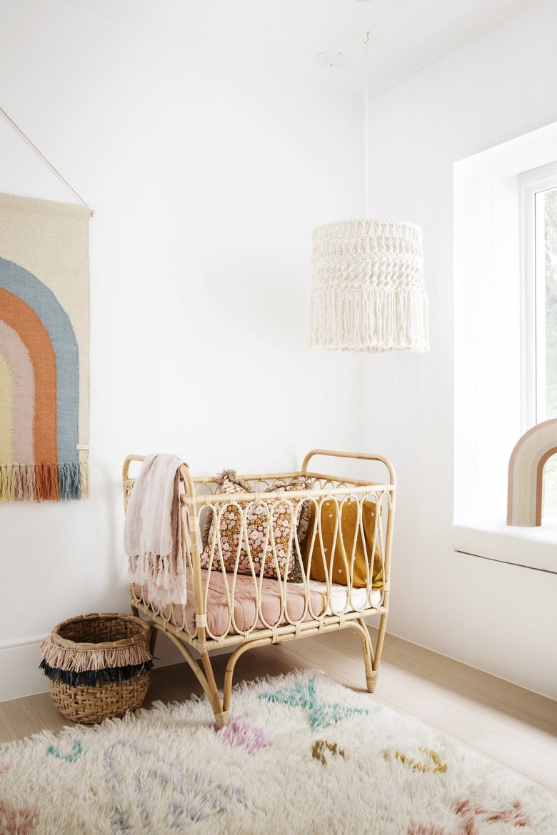 bohemian nursery with rattan crib and rainbow wall hanging