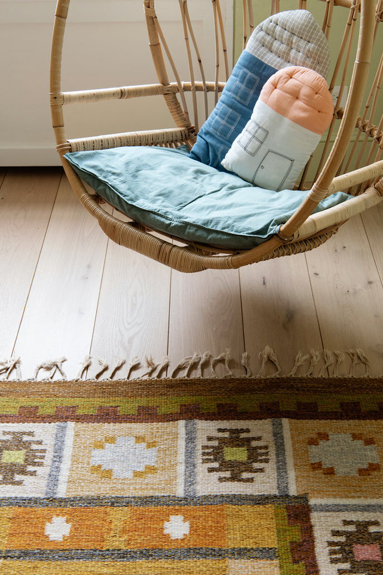 patterned ochre color rug in room with wood hanging chair