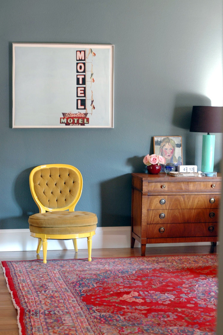 ochre color accent chair in green room with red vintage rug