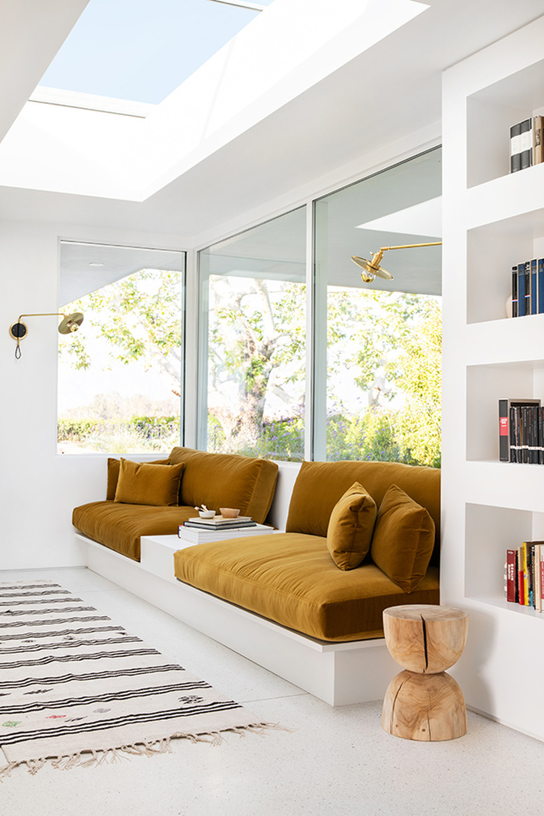 ochre color bench cushions in white sun room and library nook