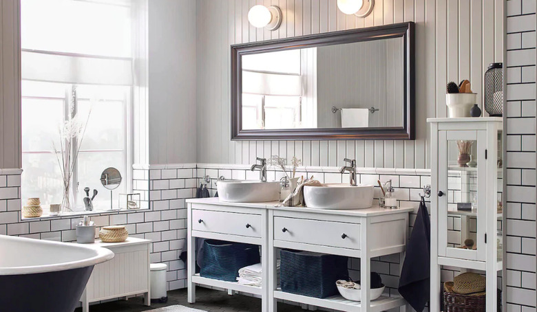 bathroom space with white tiling and two white bathroom vanities, mirror, and two light sconces above