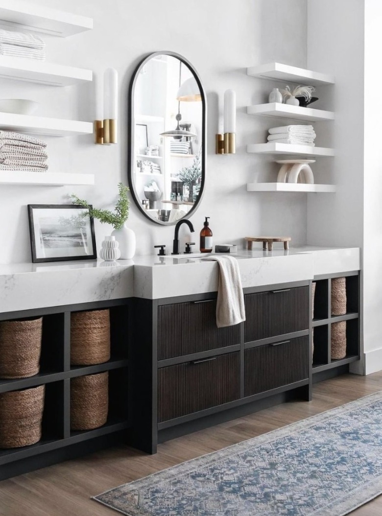 Modern bathroom with open shelves, mirror, baskets, rug, sconces.