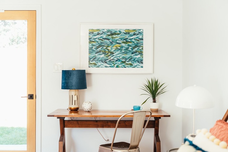 Casement door beside a wood desk with a lamp and houseplant with a Marais chair and a white dome lamp