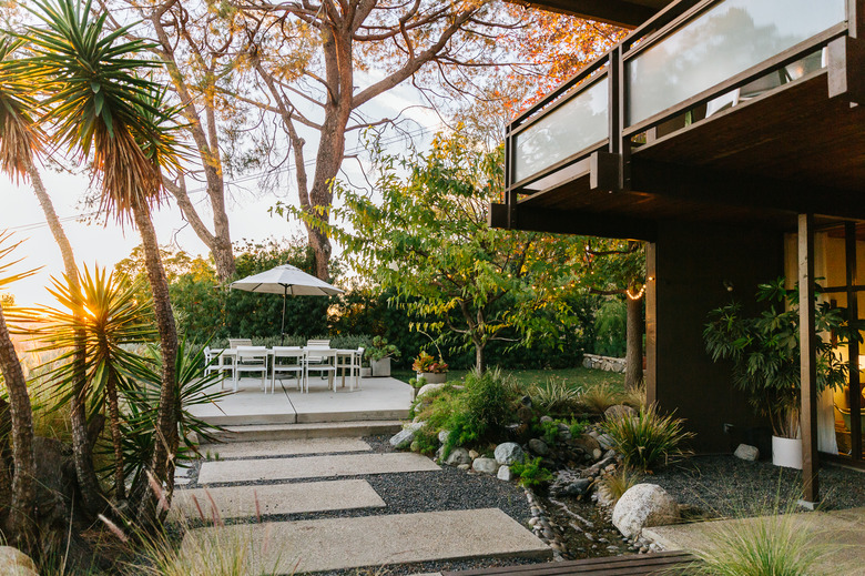 outdoor idea with seating and umbrella surrounded by trees and stone path