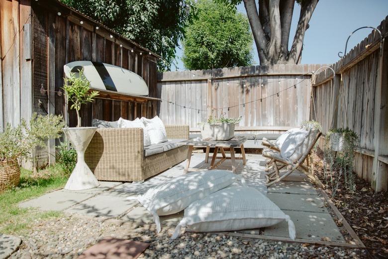 Outdoor idea for small patio design with fence, cement blocks, surfboard, and natural patio furniture