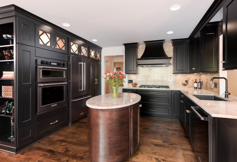 Oval kitchen island with dark polished wood base and off white countertop.