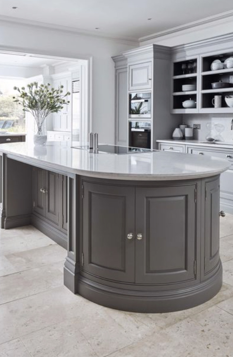 Oval shaped kitchen island with gray cabinets and white countertop.