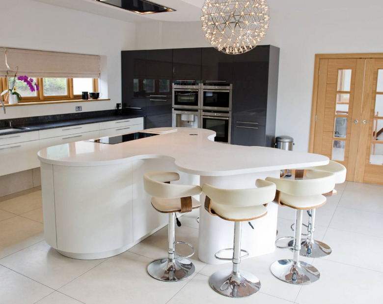 Oval kitchen island with curved dining area connected. All white cabinets and countertop.