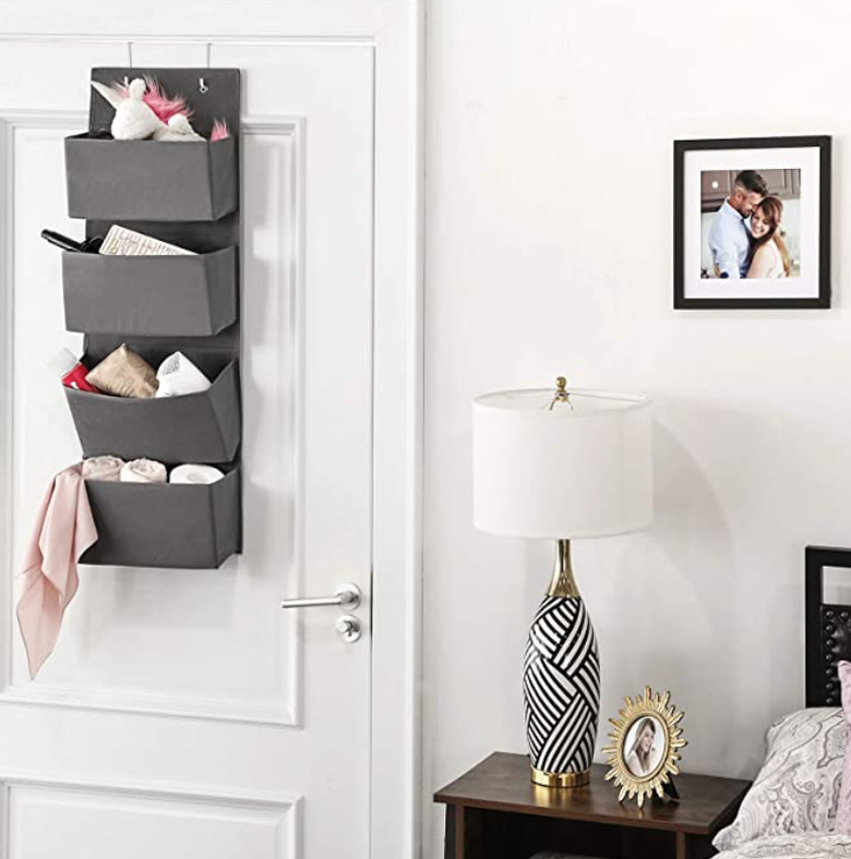 Over the Door Storage with Gray storage bins hanging on door, lamp, photos, nightstand.