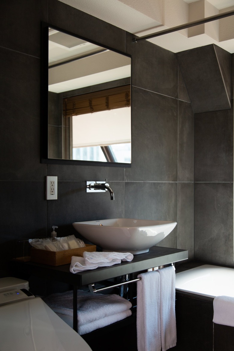 a white basin sink contrasts with dramatic dark gray walls in the bathroom