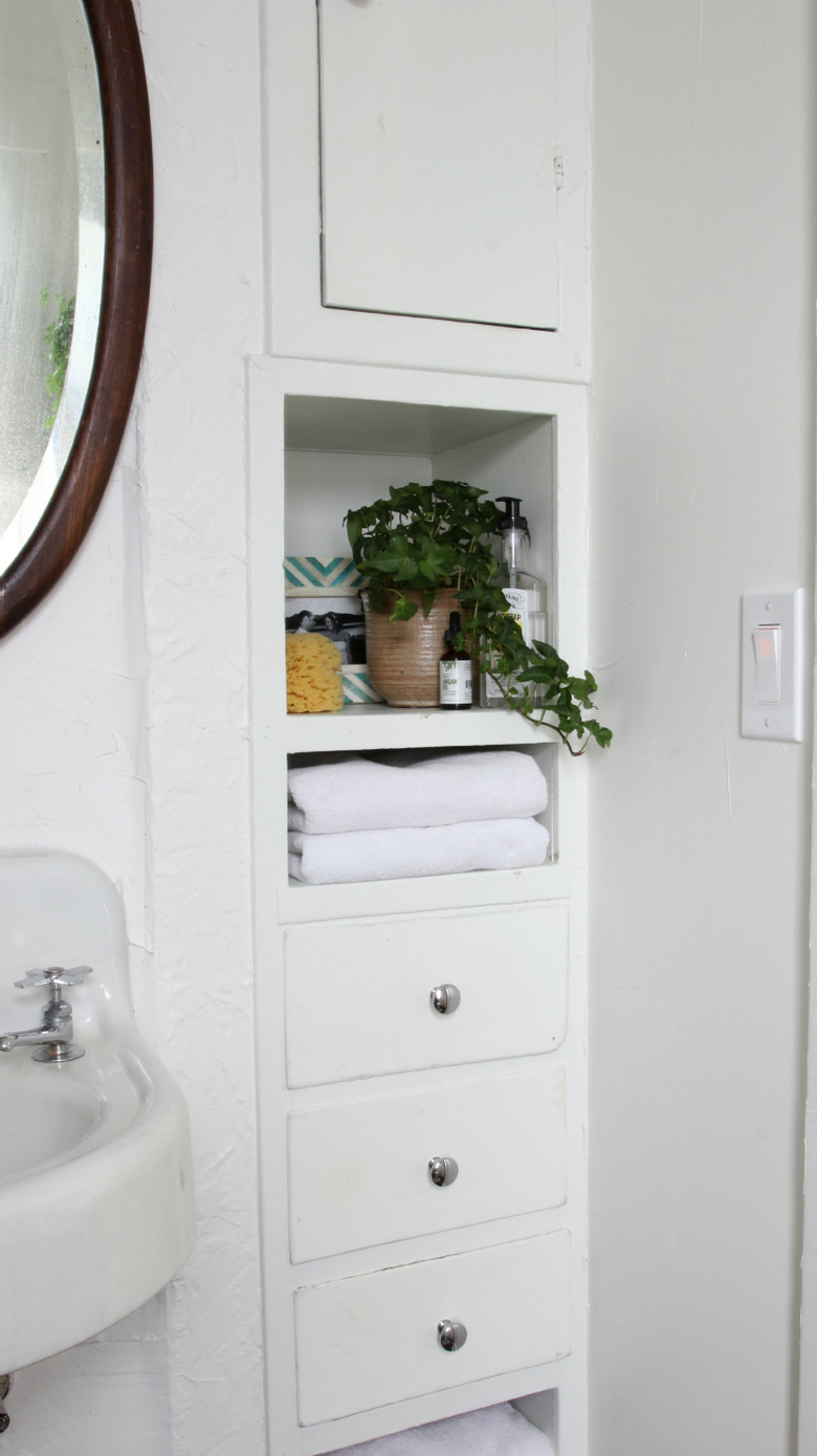 bathroom towel storage idea with round mirror and bult-in cabinet storage