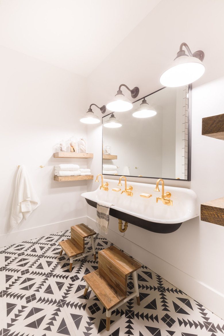 bathroom towel storage idea in white and black bathroom with patterned floor and trough sink