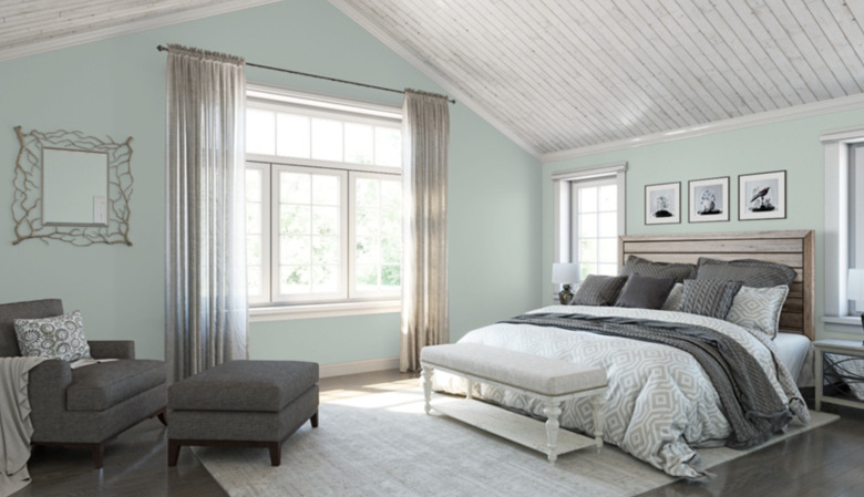 sherwin-williams rainwashed paint color on bedroom walls featuring bed, armchair, ottoman, and curtains