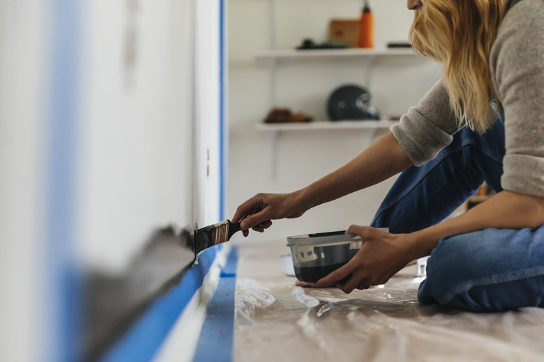 Woman sitting painting wall at home