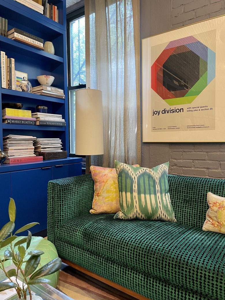 Deep green upholstered sofa next to a blue bookshelf