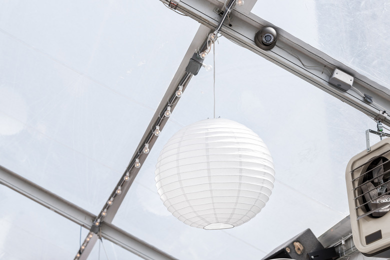 Closeup of hanging one white paper party ball or sphere light lantern from ceiling in restaurant building venue with fan, speakers