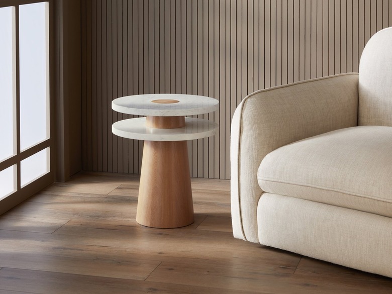 A side table with a simple conical base with two slabs of white marble layered to create a round top.