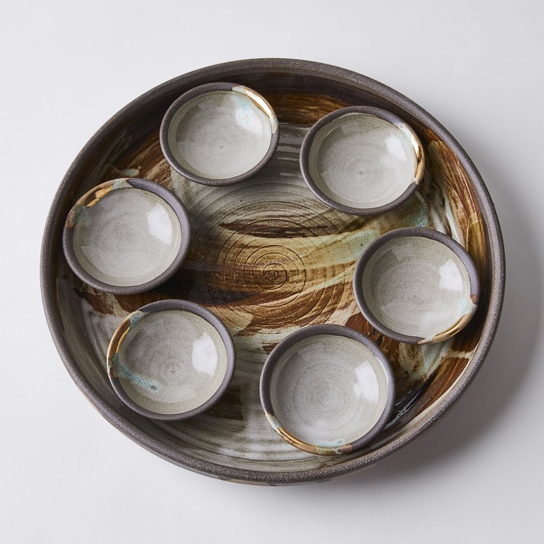 A ceramic Seder plate colored with strokes of brown, blue, green, and gray.