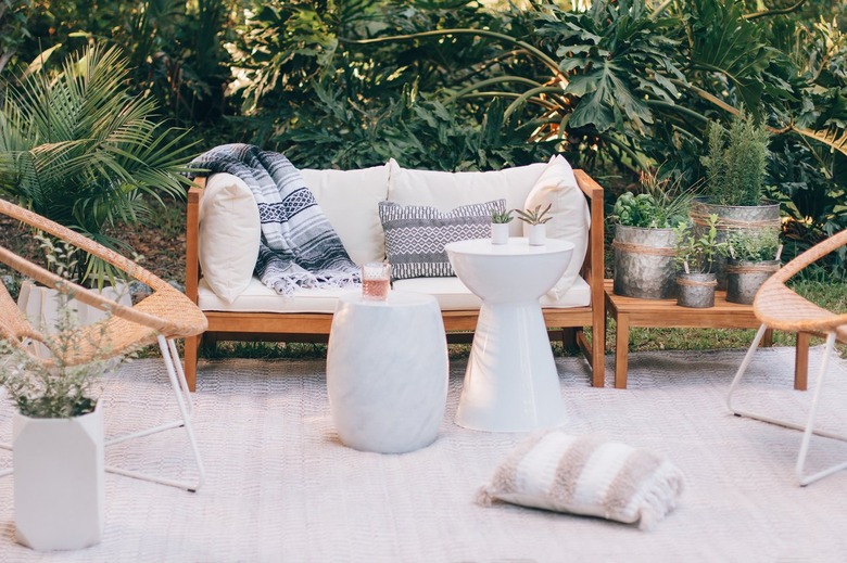 White cushioned patio furniture with ceramic stools and metal planters