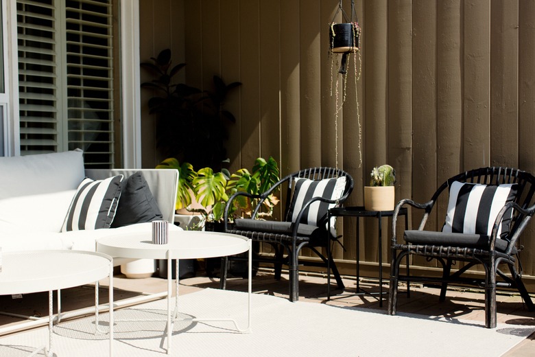 Patio couch, chairs and black and white pillows, and white coffee table