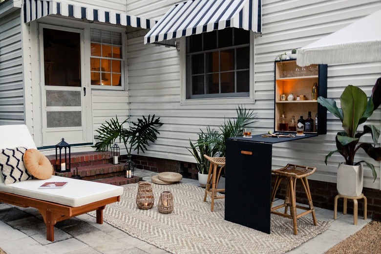 Patio with a black plywood bar table-cabinet set, tropical plants, lanterns, rattan furniture, and black-white accents