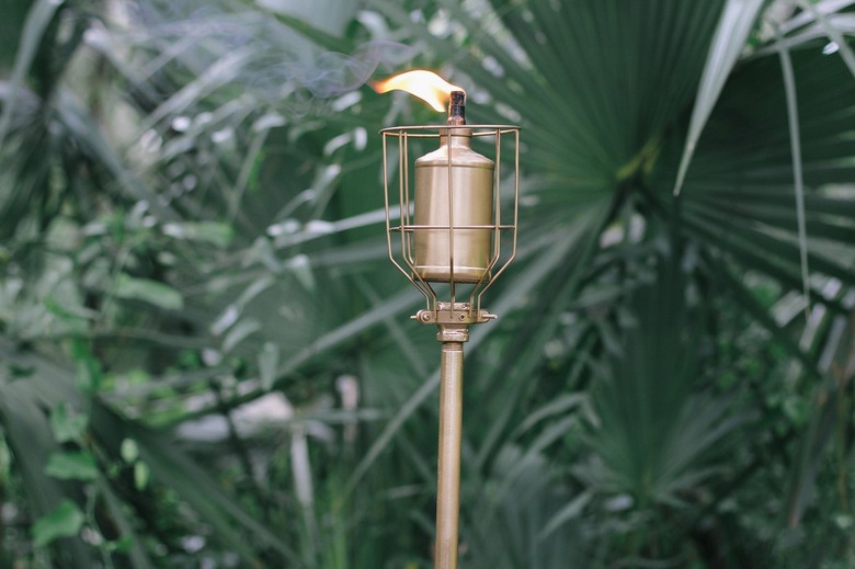 an industrial diy outdoor torch with a gold metallic finish and a lit flame