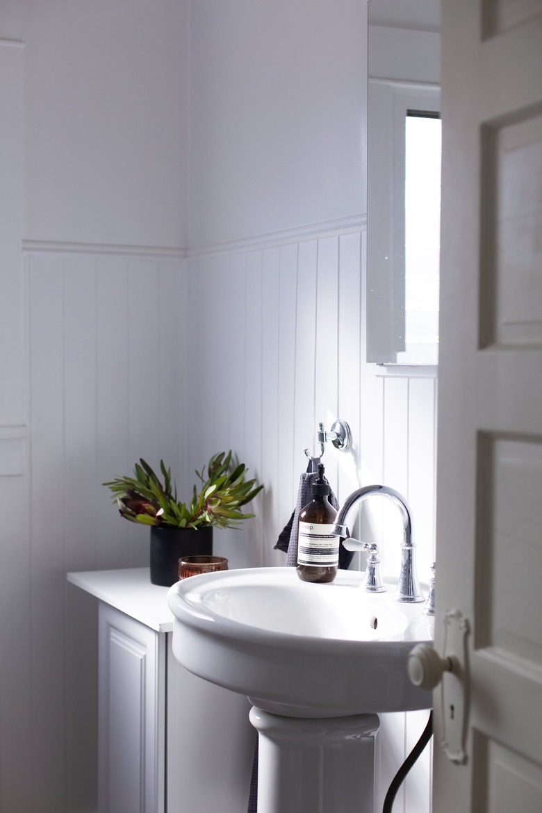 Pedestal Sink Storage Ideas with walls, wainscotting, sink, and vanity are all white in this bathroom