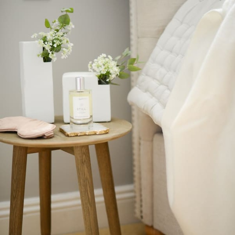 Wooden minimal nightstand with white vases, pillow spray, and blush eye mask