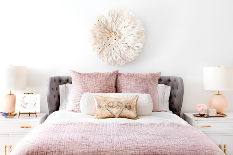 bedroom with light pink bedding and tufted gray headboard