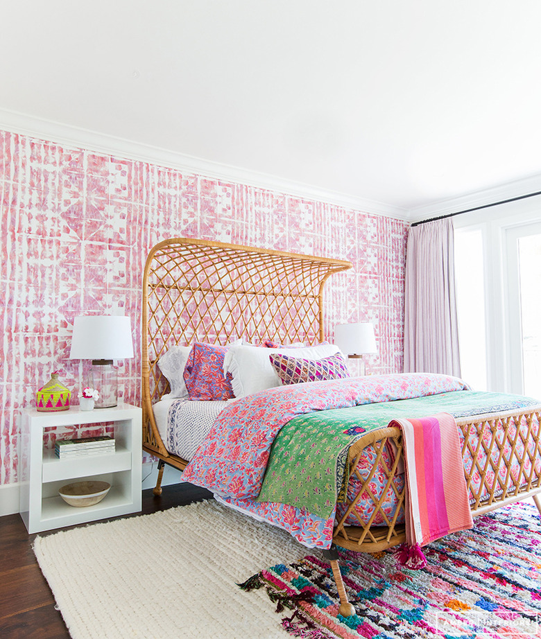 pink bohemian bedroom with woven rattan bed and pattern wallpaper