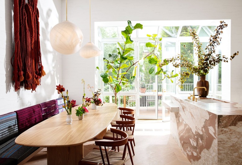 white kitchen with pink marble island and wooden table