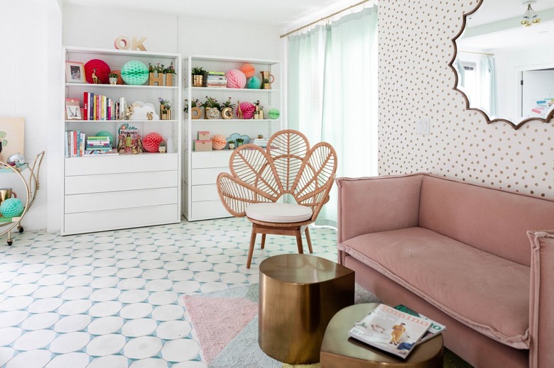 pink room ideas with Pink couch in room with white walls, tiled floors and wallpaper, oval mirror, cane side chair and hold coffee tables.