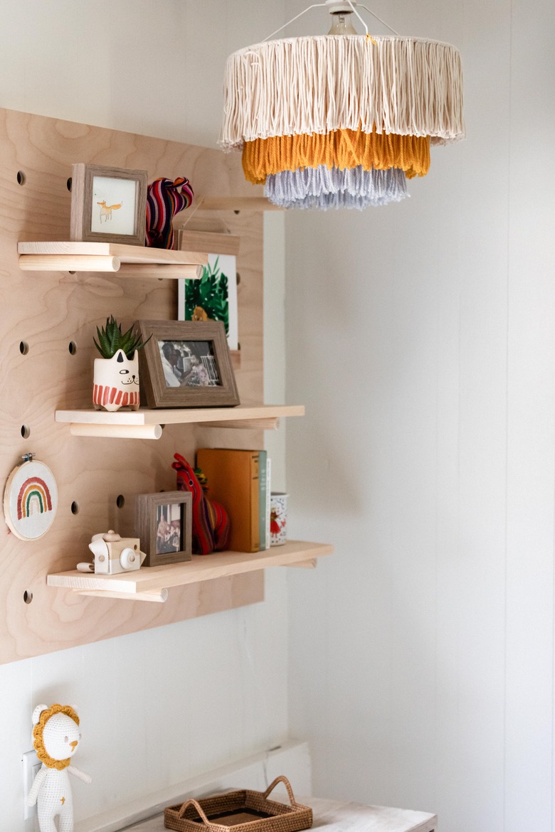 playroom idea with fringe chandelier and pegboard shelving