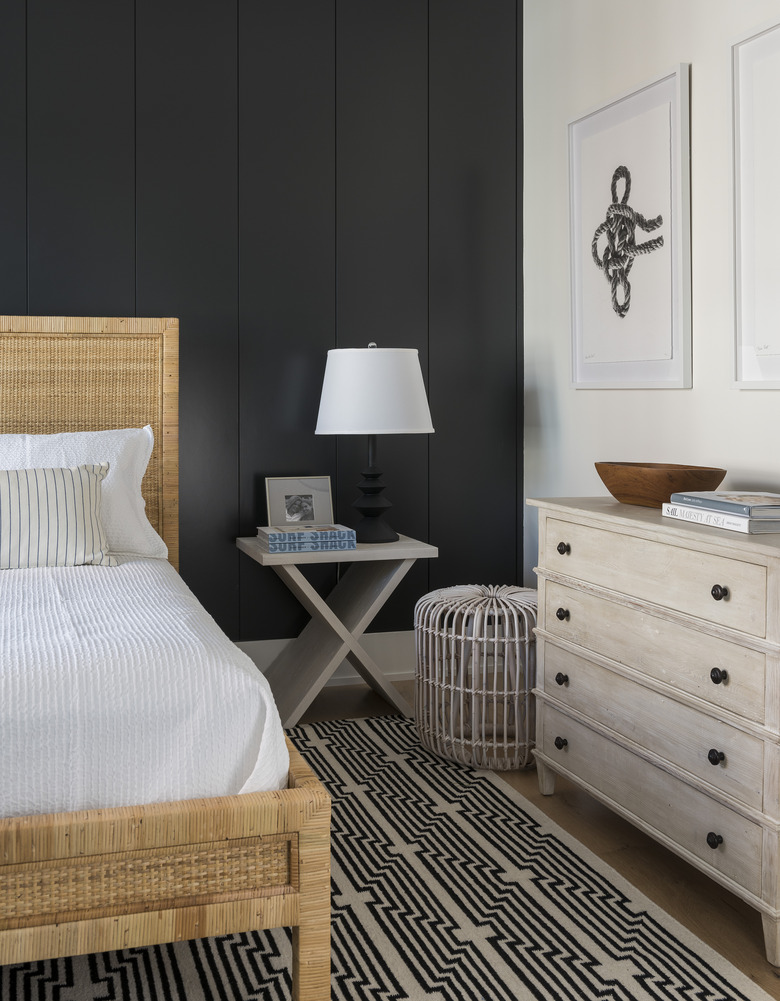 Coastal black bedroom idea with woven rattan bed and area rug