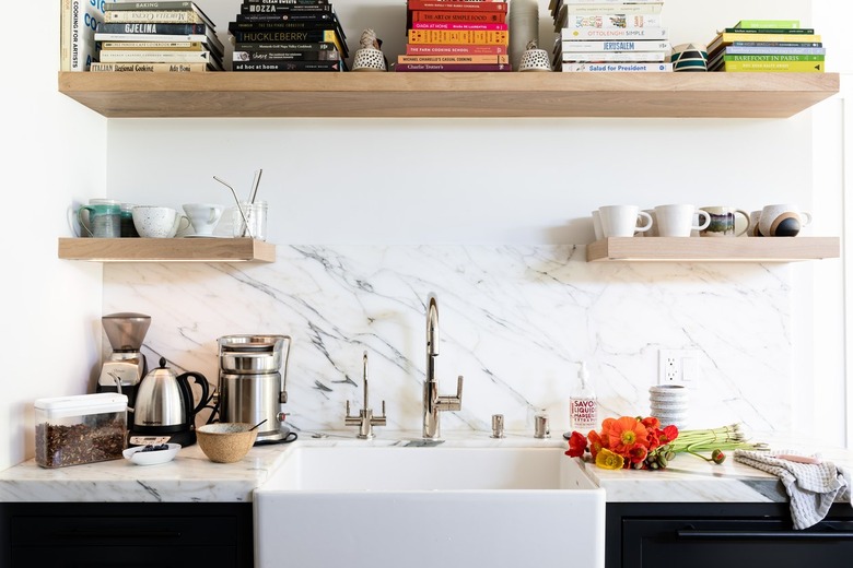 Electric Stove Burner in White granite wall of a kitchen with white sink and wood shelving with books