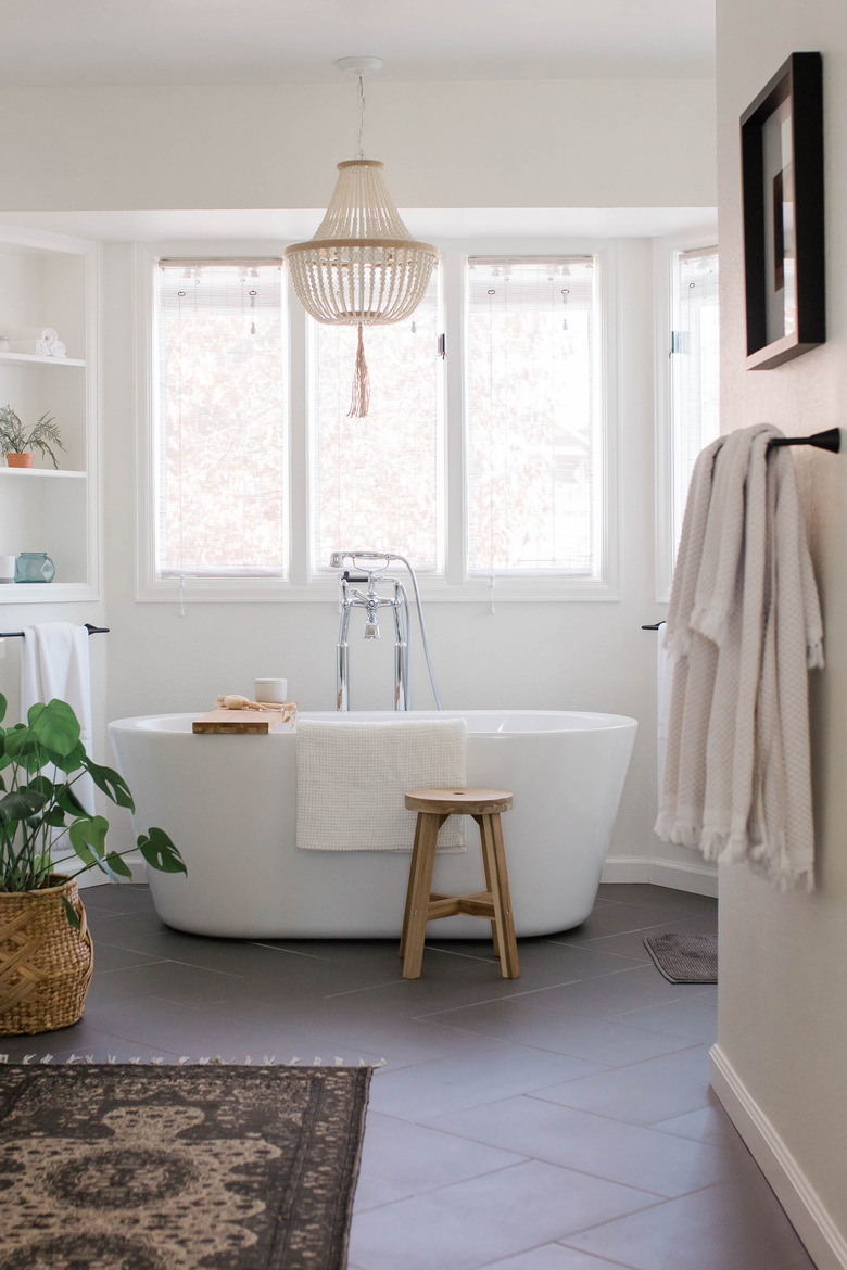 White soaking tub with beaded chandelier and polished chrome shower fixtures