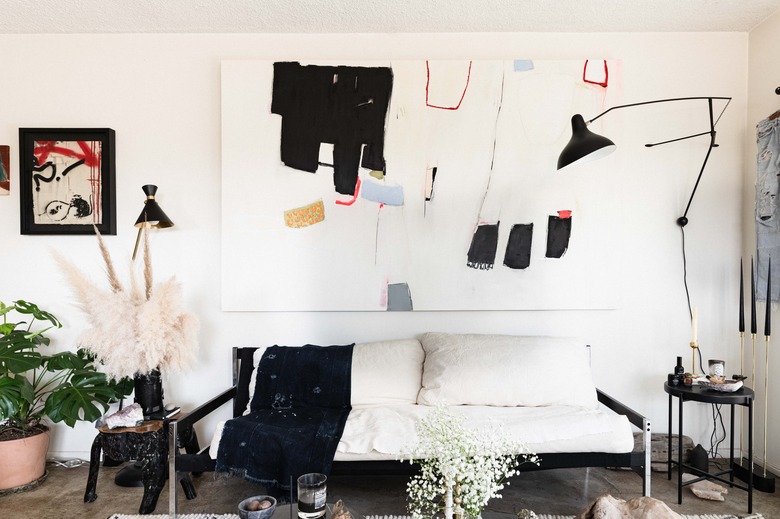 living room focus on couch with abstract art overhead and a concrete floor