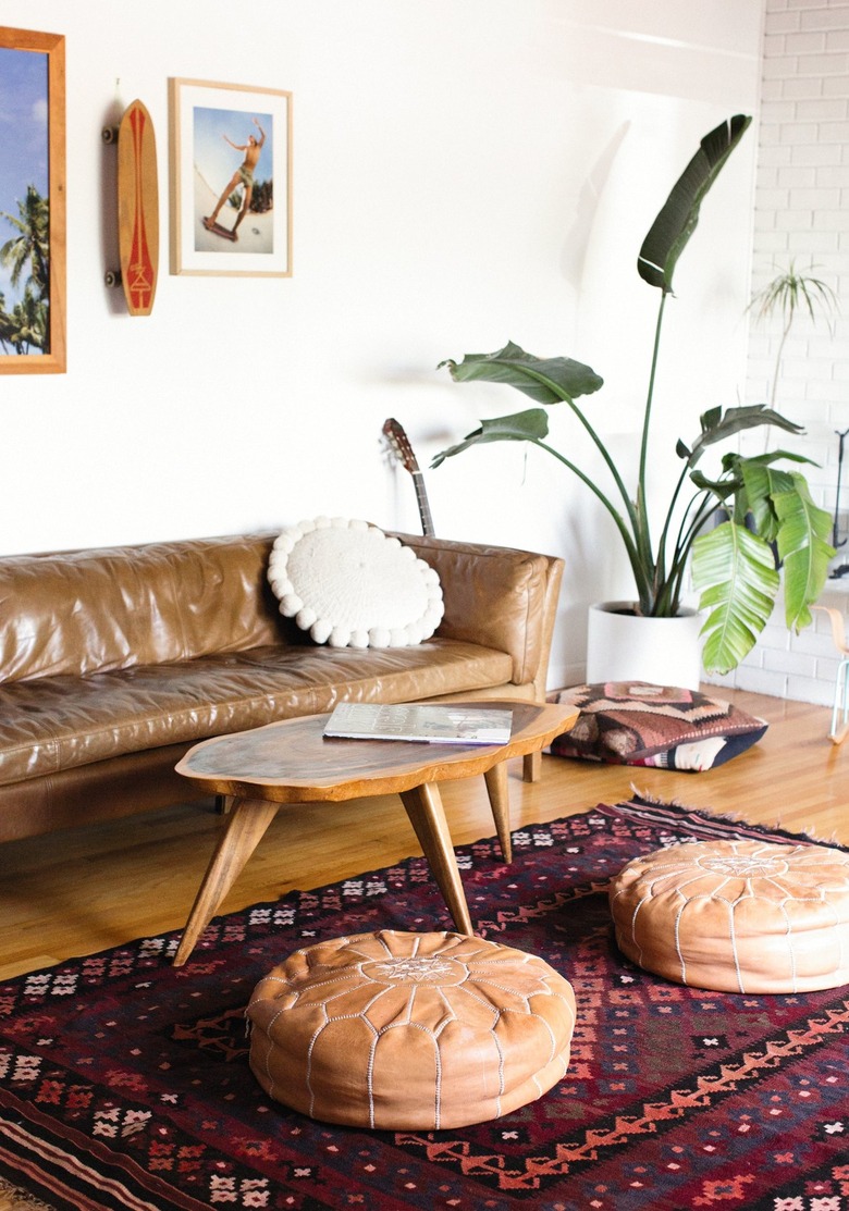 Living room with leather couch wood table and leather poufs on patterned carpet