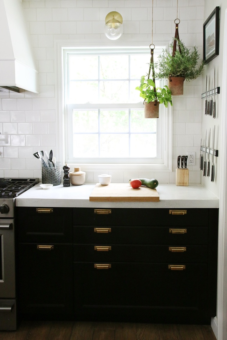 kitchen window idea with rustic potted herbs hanging in the corner of a modern black-and-white kitchen