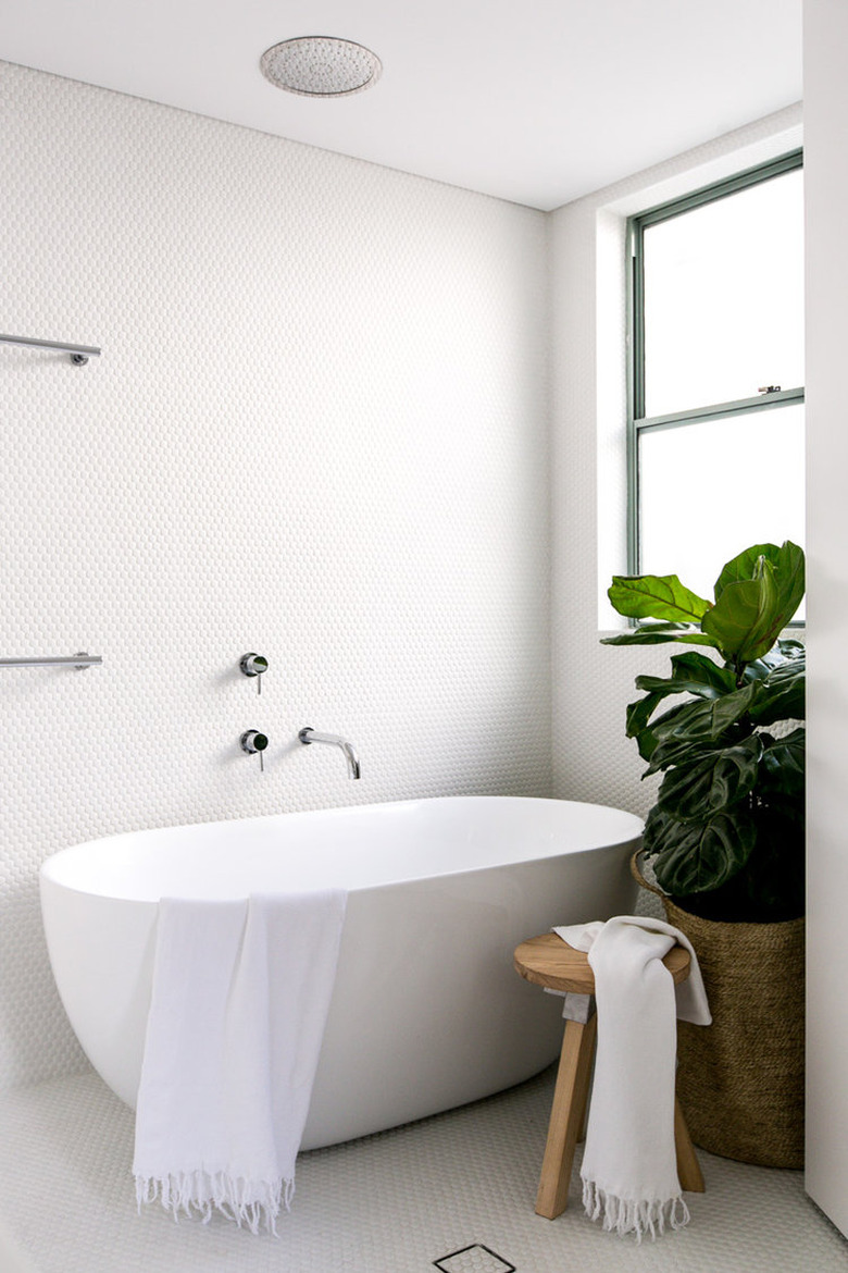 all-white bathroom with round penny tile mosaic on walls and floor